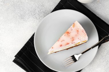 Masadaki beyaz tabakta bir parça peynirli kek