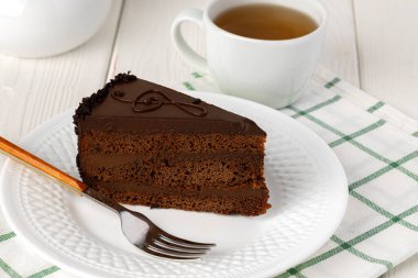 Masadaki beyaz tabakta bir parça çikolatalı pasta.