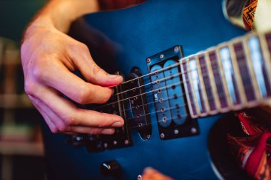 Erkek elinin karanlıkta elektro gitar çalmasını kapat.