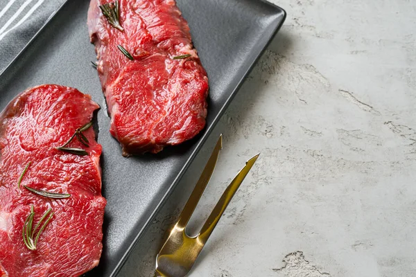 Dos filetes frescos de carne cruda en plato de cerámica negra — Foto de Stock