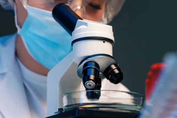 Femme scientifique regardant à travers un microscope en laboratoire — Photo