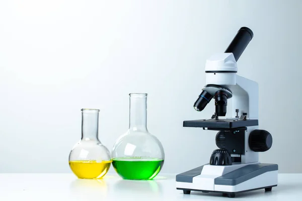 Laboratóriumi mikroszkóp laboratóriumi üvegárukkal az asztalon — Stock Fotó