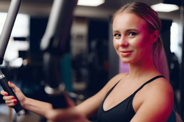 Junge kaukasische blonde Frau trainiert Hände in einem Fitnessstudio — Stockfoto