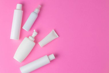 Kozmetik şişeleri pembe arka planda yatıyordu.