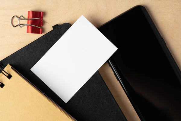 テーブルの上に空白の名刺と黒のスマートフォンの画面のモックアップ — ストック写真