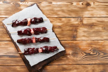 Tahtadaki şişler üzerinde çiğ ciğer kebabı.