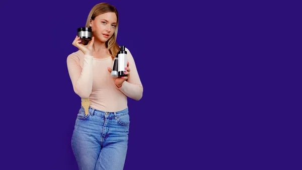 Attraktive junge Kaukasierin präsentiert Kosmetikflaschen — Stockfoto