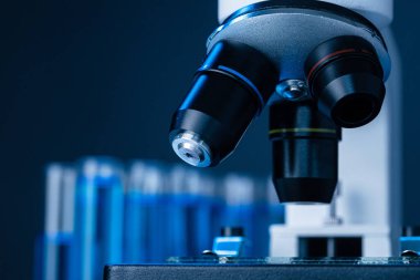 Laboratuvar mikroskobunu mavi sıvı test tüpleriyle kapatın.