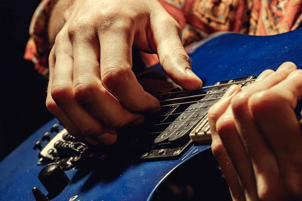 Primer plano de mano masculina tocando la guitarra eléctrica en la oscuridad — Foto de Stock