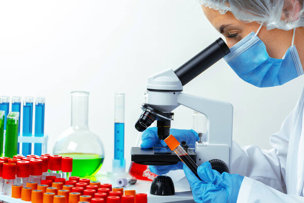 Woman scientist looking through a microscope in laboratory