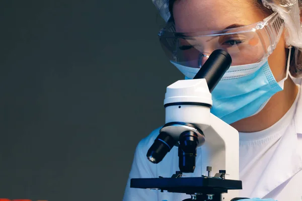 Femme scientifique regardant à travers un microscope en laboratoire — Photo