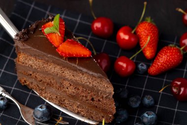 Taze böğürtlenlerle servis edilen bir parça çikolatalı kek.