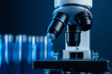 Laboratuvar mikroskobunu mavi sıvı test tüpleriyle kapatın.