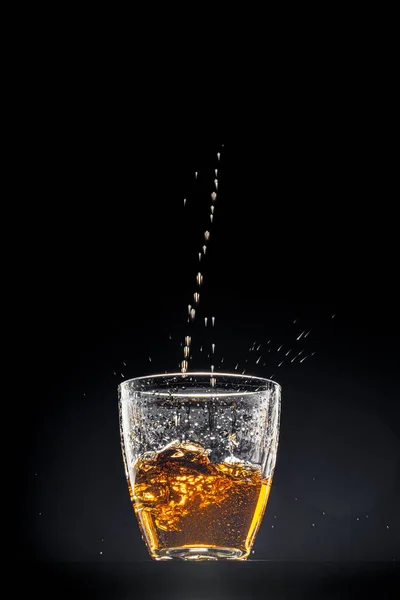 Whisky in einem Glas auf schwarzem Hintergrund — Stockfoto