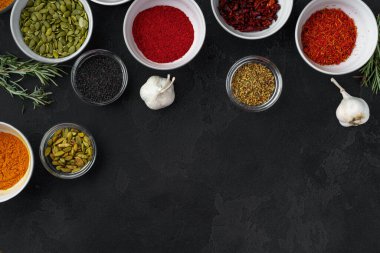 Koyu arkaplanda çeşitli baharatlar bulunan kaseler.