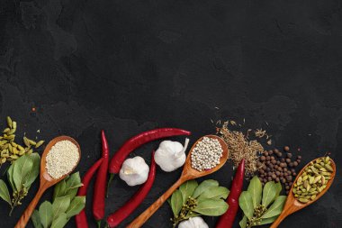 Siyah arka planda çeşitli baharatlı ahşap kaşıklar.