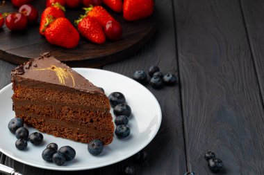 Taze böğürtlenlerle servis edilen bir parça çikolatalı kek.