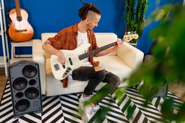 Odasında elektronik gitar çalan Kafkasyalı genç bir adam.