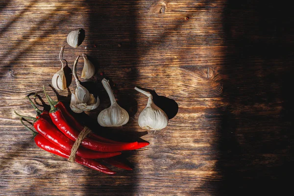 Pieprz czosnkowy i chili na ciemnym drewnianym stole — Zdjęcie stockowe