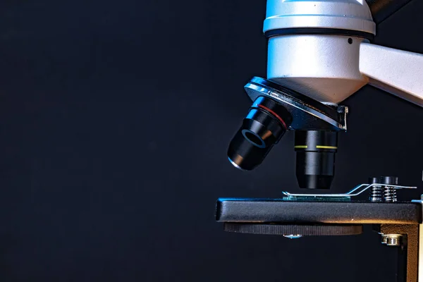 Microscopio con lentes cerca sobre fondo oscuro —  Fotos de Stock