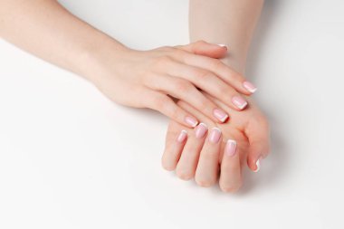 Beyaz arka planda manikürlü, bakımlı kadın elleri.