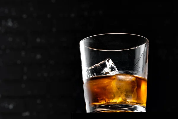 Whisky glas mot mörk svart grunge vägg — Stockfoto