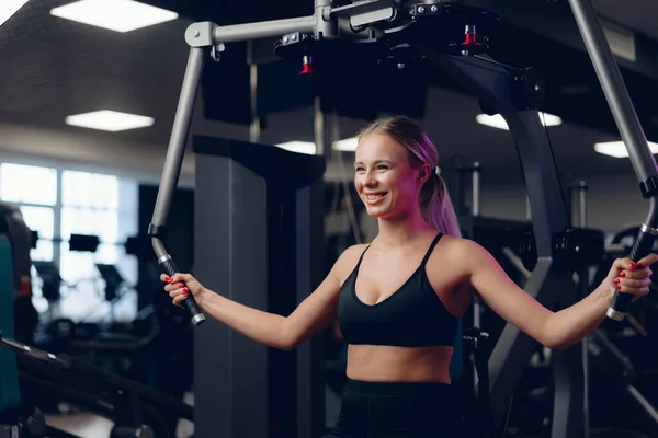 Junge kaukasische blonde Frau trainiert Hände in einem Fitnessstudio — Stockfoto