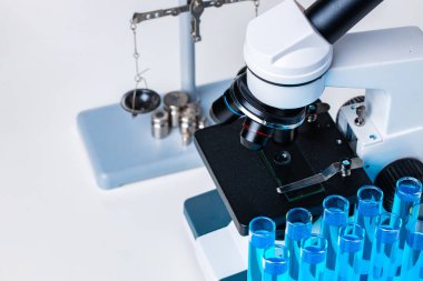 Laboratuvar mikroskobunu mavi sıvı test tüpleriyle kapatın.