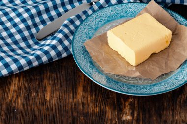 Mutfak masasında mavi havluyla tereyağını tabakta kes