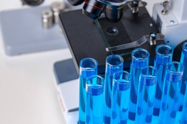 Laboratuvar mikroskobunu mavi sıvı test tüpleriyle kapatın.