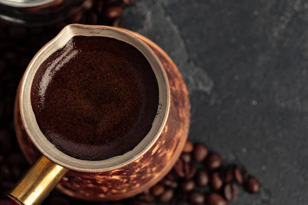 Кофейные зерна и турок на темной поверхности — стоковое фото