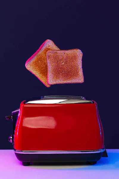 Neon ışıkta tost makinesinden fırlayan iki dilim tost. — Stok fotoğraf