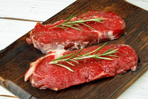 Bifes de vitela de churrasco com alecrim em tábua de madeira — Fotografia de Stock