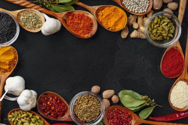 Siyah arka planda çeşitli baharatlı ahşap kaşıklar.