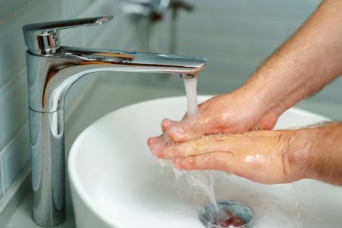 Erkek ellerinin lavabonun üstünde sabunla yıkandığı fotoğrafı kapat.