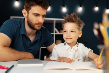 Baba ve oğul birlikte okul ödevi yapıyorlar.