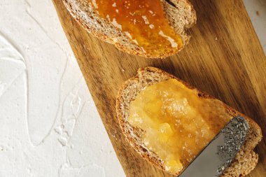 Tahtada meyve reçeli ile kaplı bir dilim ekmek.