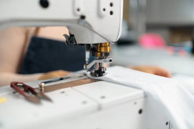 Dikiş makinesiyle bir terziye yakın dur.