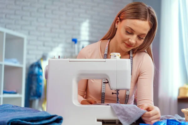 Joven costurera trabajando en su máquina de coser en fábrica textil — Foto de Stock