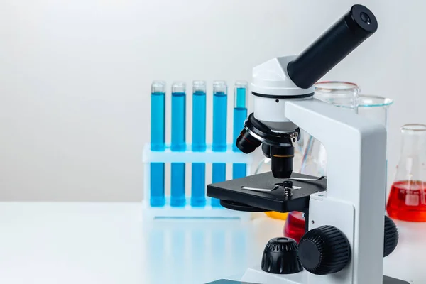 Nahaufnahme des Labormikroskops mit einem Satz Reagenzgläser mit blauer Flüssigkeit — Stockfoto