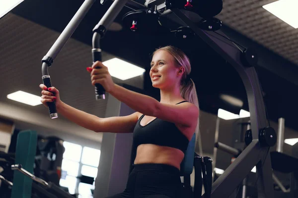 Junge kaukasische blonde Frau trainiert Hände in einem Fitnessstudio — Stockfoto