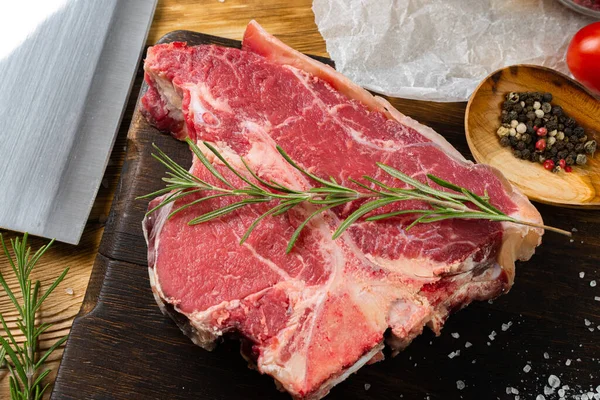 Filete crudo de hueso en T con hierbas sobre tabla de madera —  Fotos de Stock