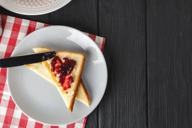 Tahta masada çilek reçelli kızarmış ekmek dilimleri.