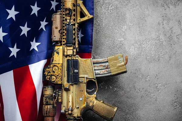 Americká bojová vlajka a útočná puška u zdi. zavřít. — Stock fotografie