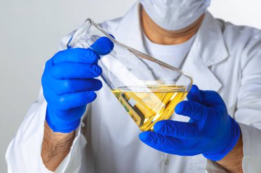 Bilim adamlarının elleri laboratuarda analiz için cam bir odada sıvı tutuyorlar.