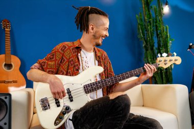 Odasında elektronik gitar çalan Kafkasyalı genç bir adam.