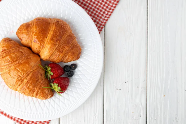 Fresh croissant decorated with berries on white wooden board — Stock Photo, Image