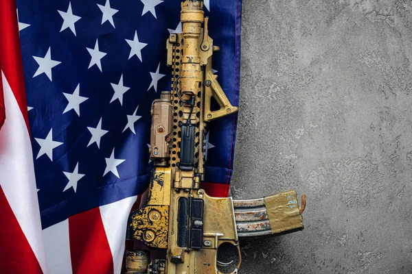 U.S. battle flag and assault rifle near the wall. close up. — Stock Photo, Image