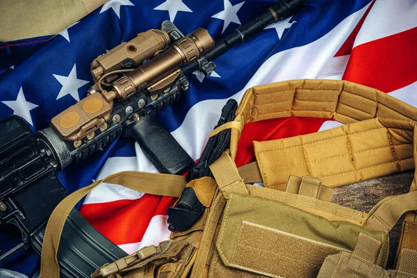 Bandera de batalla estadounidense y rifle de asalto en la mesa de madera . — Foto de Stock