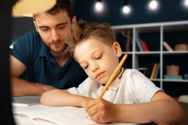 Baba ve oğul birlikte okul ödevi yapıyorlar.